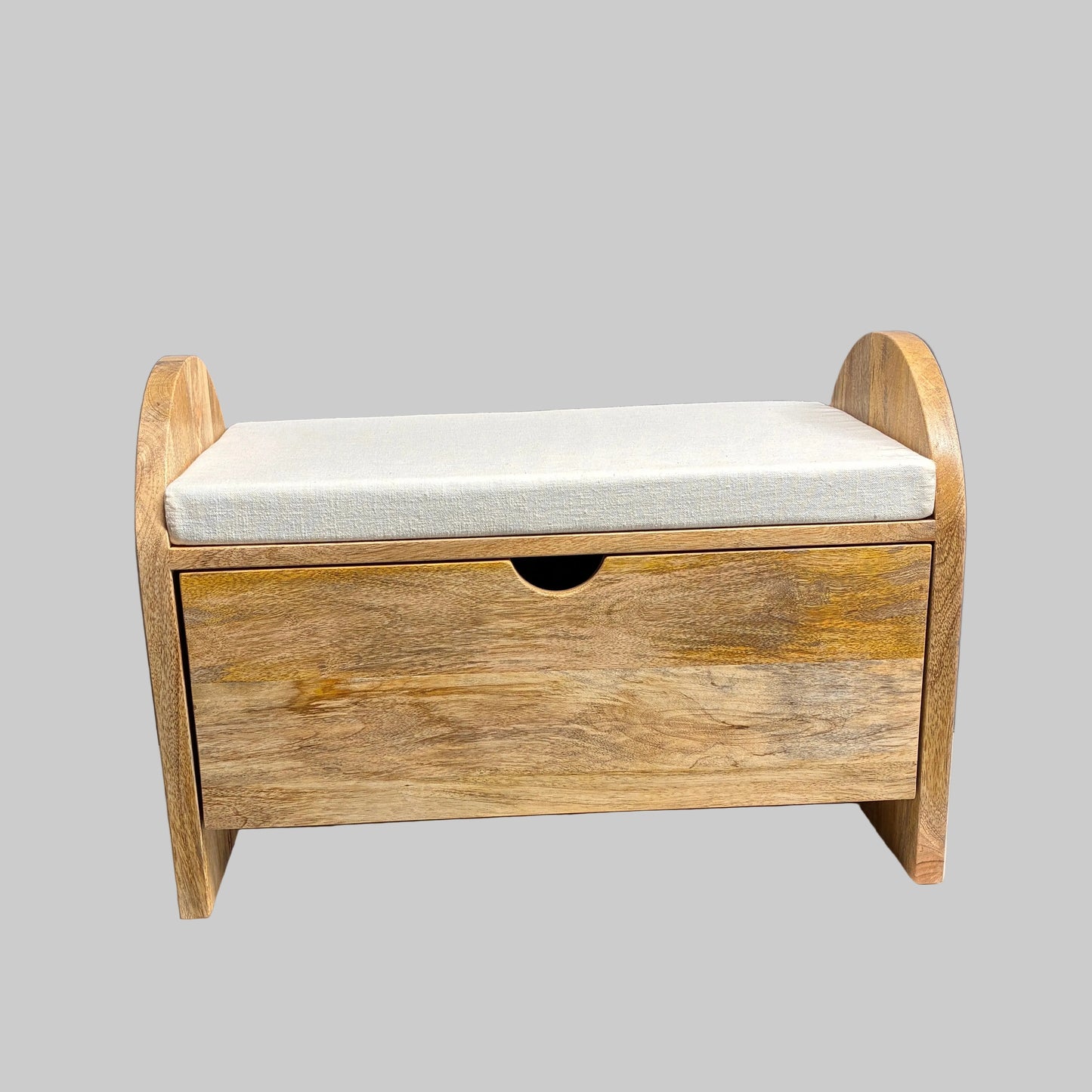 A rustic wooden storage bench with a single drawer and a light beige fabric cushion, displayed on a white-covered table in a workshop setting.