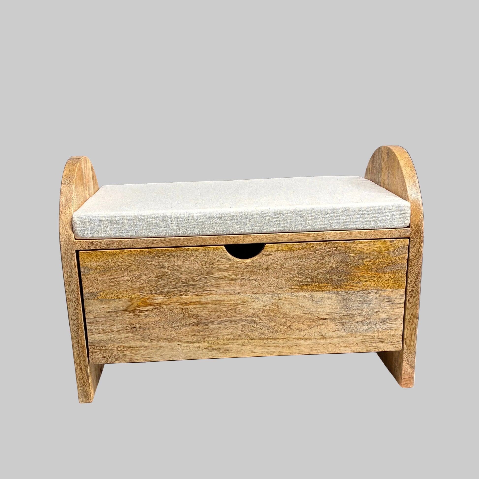 A rustic wooden storage bench with a single drawer and a light beige fabric cushion, displayed on a white-covered table in a workshop setting.