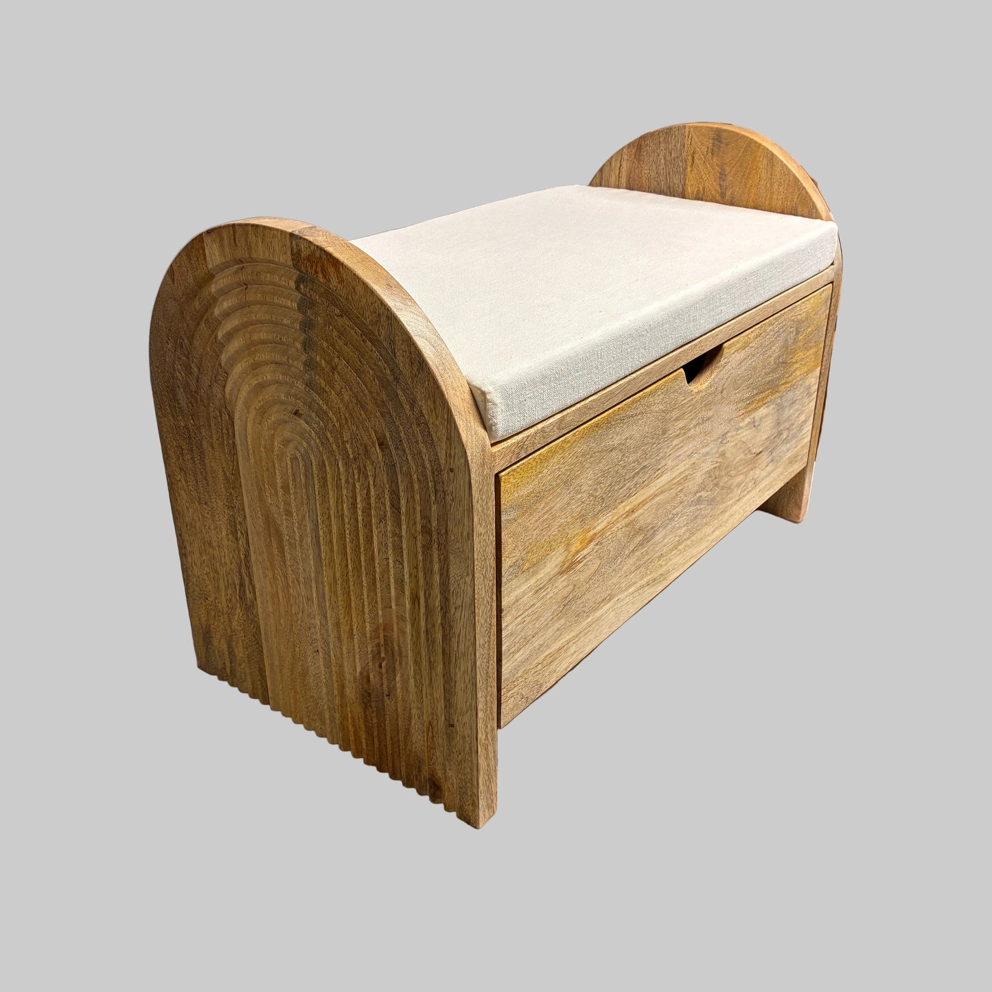 A rustic wooden storage bench with a curved backrest and a single front drawer, shown on a workbench in a workshop setting. The bench has a light natural wood finish and is topped with a cream-colored fabric cushion.