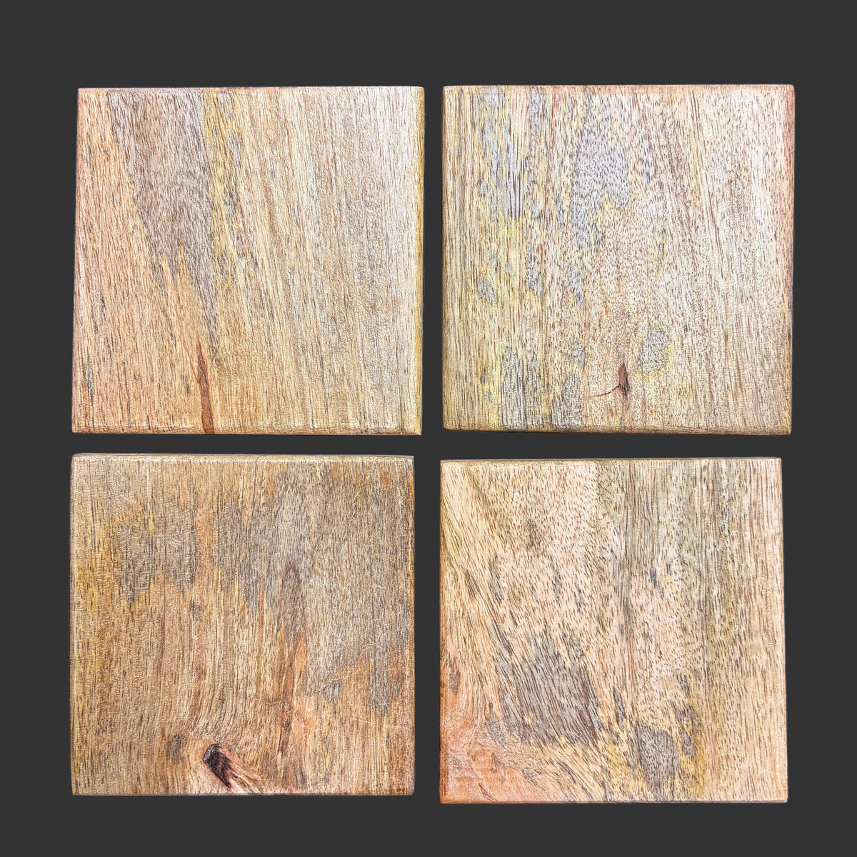 Four square wood coasters with natural grain patterns in warm brown, beige, and gray tones, arranged in a 2x2 grid on a dark charcoal background.