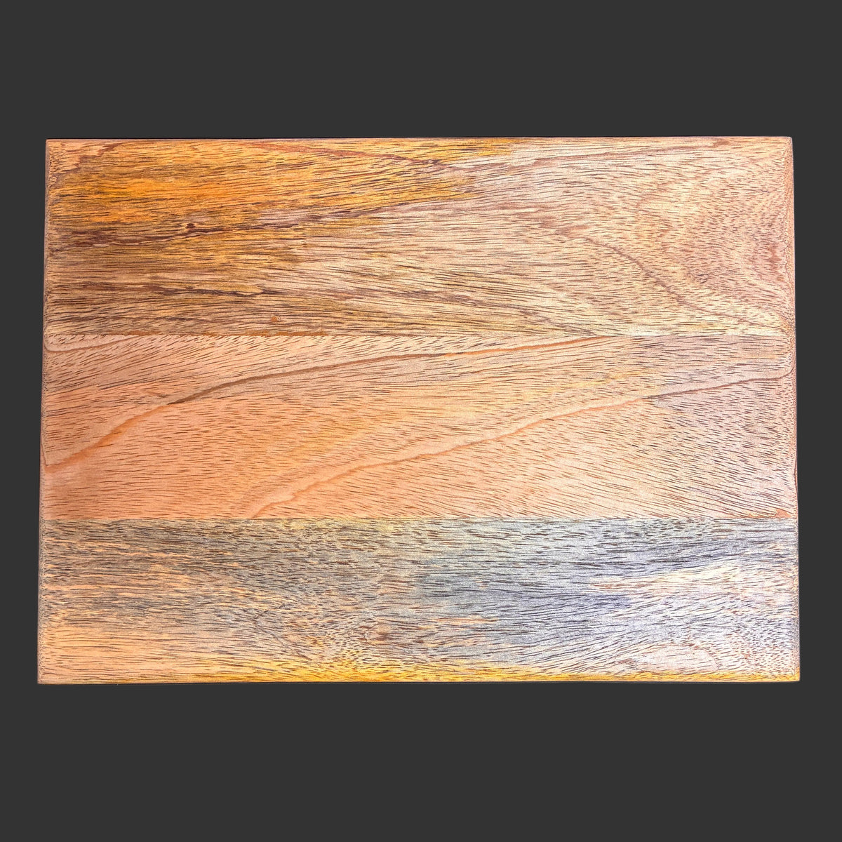 A square wooden board or plaque with a richly textured, rustic wood grain pattern in warm brown, orange, and gray tones, displayed flat against a dark charcoal background.