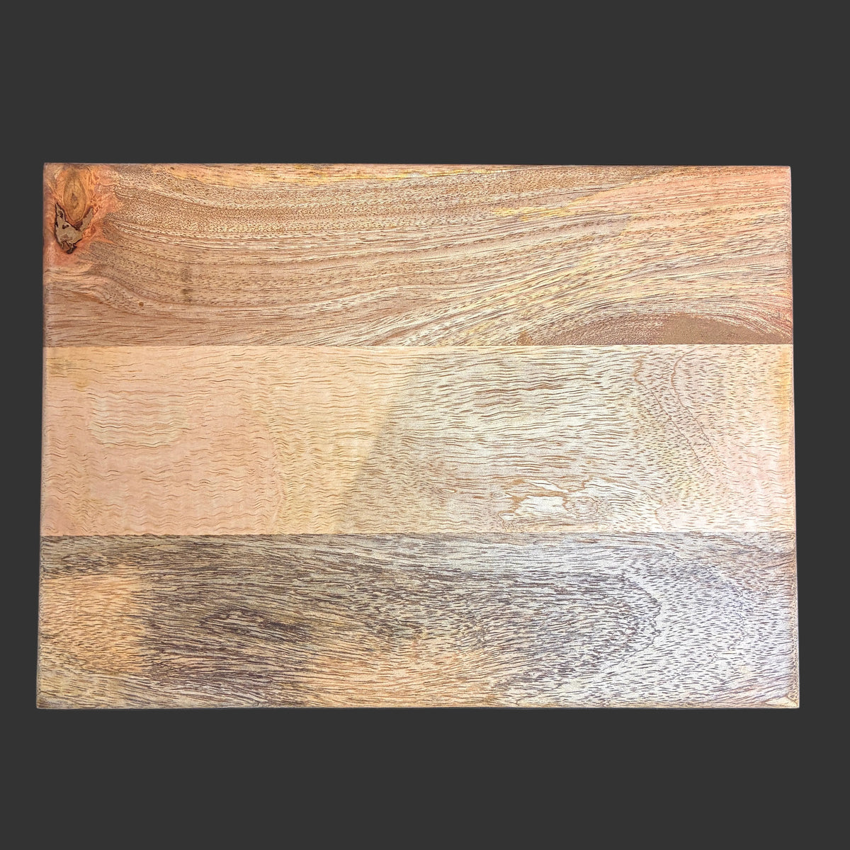 A rectangular wooden board with three horizontal bands of varying wood tones and grain patterns, photographed from above on a dark background.