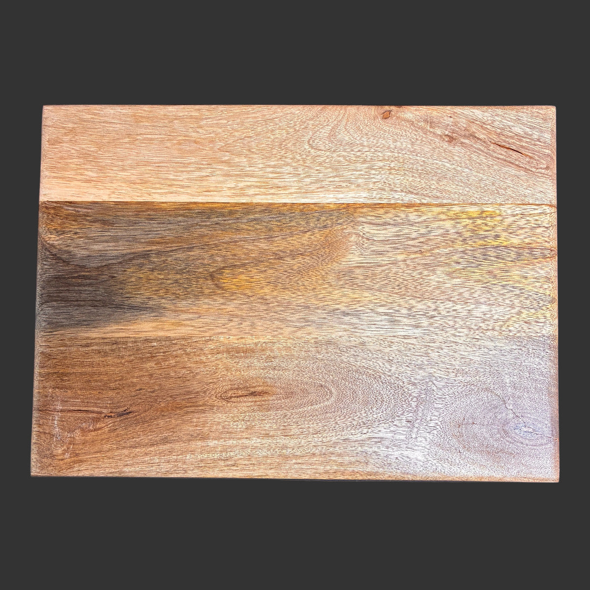 A rectangular wooden board with a natural wood grain pattern, featuring a lighter tan section on the top half and a darker brown section on the bottom half, set against a dark gray background.
