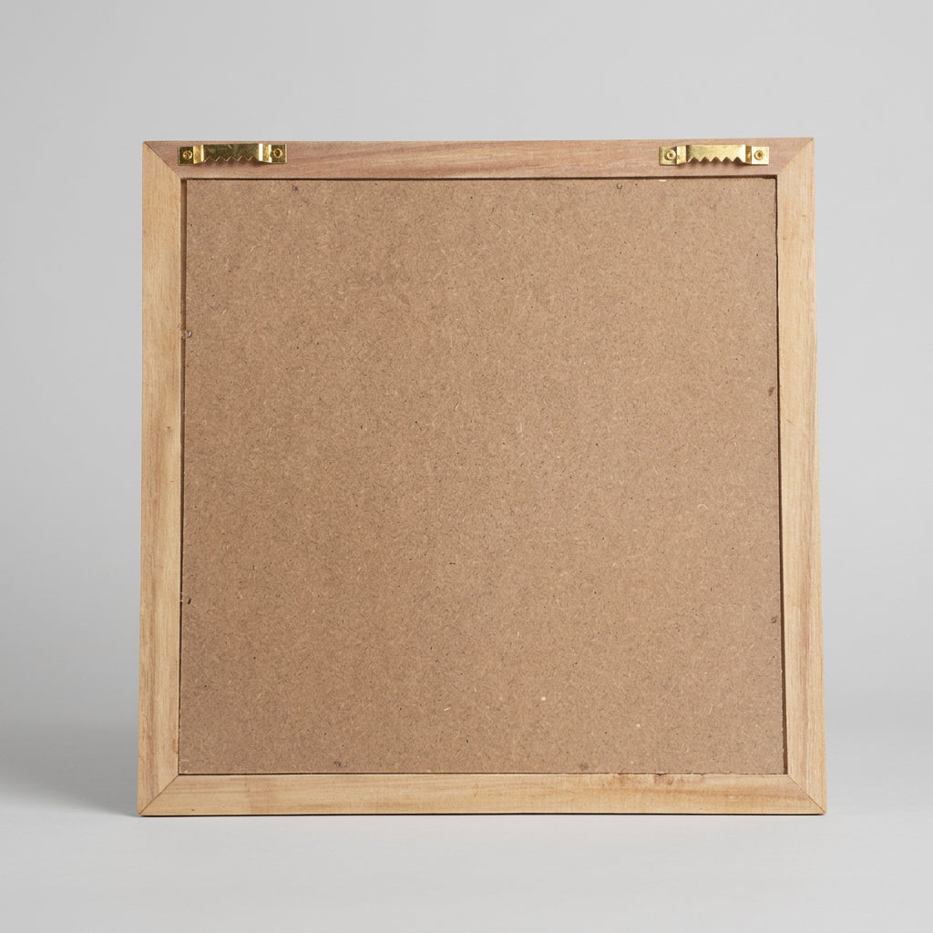 A square picture frame with a light gray wood-grain border and a gray backing board, photographed from above on a corrugated cardboard background.