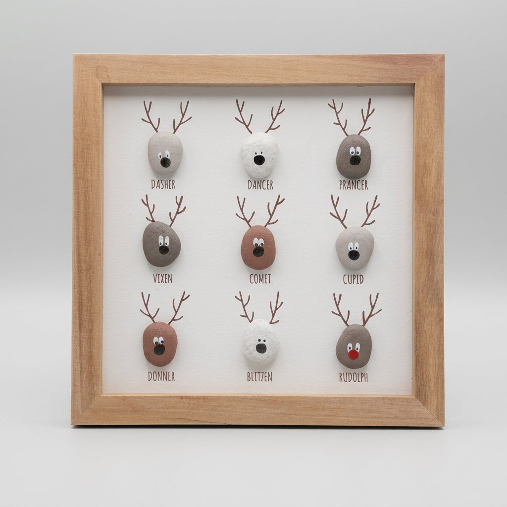 A framed square art print featuring nine hand-painted pebble reindeer faces with names underneath, displayed on a brown wooden background.