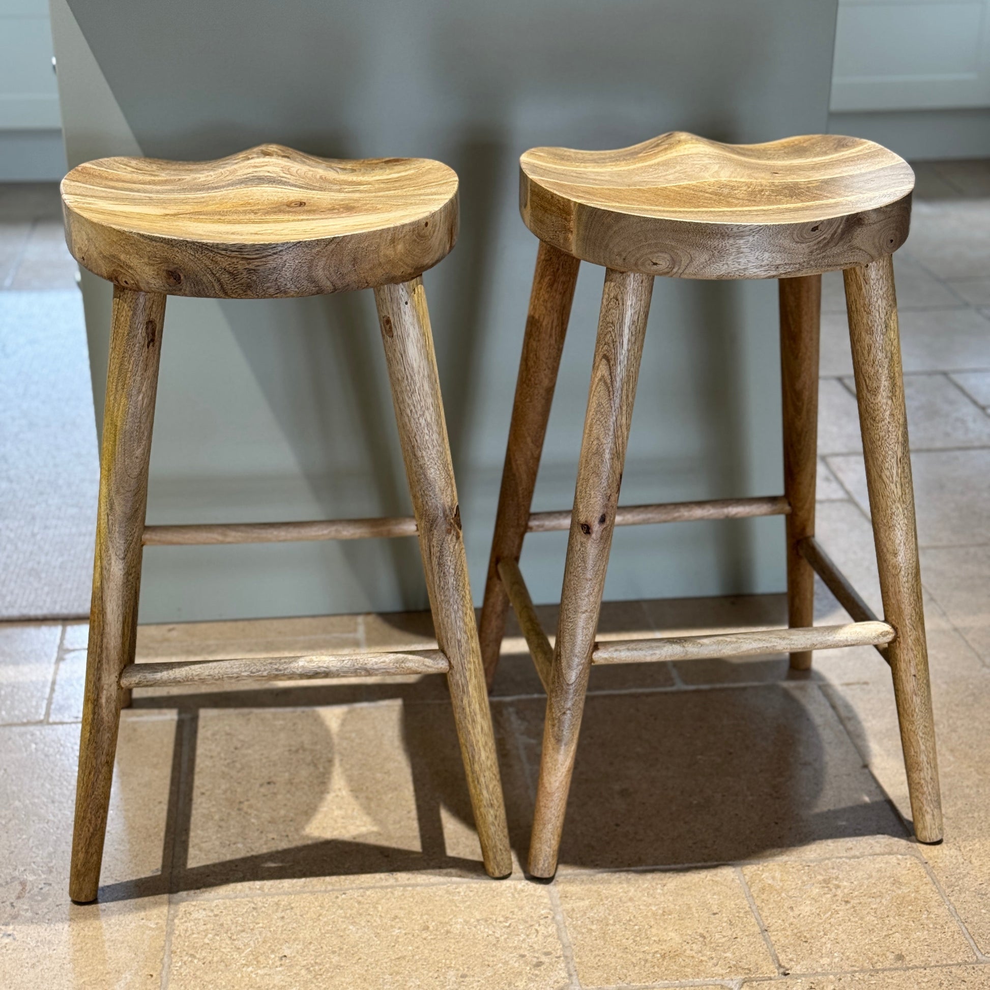 Pair of Mango wood bar stools with scalloped seat in a kitchen