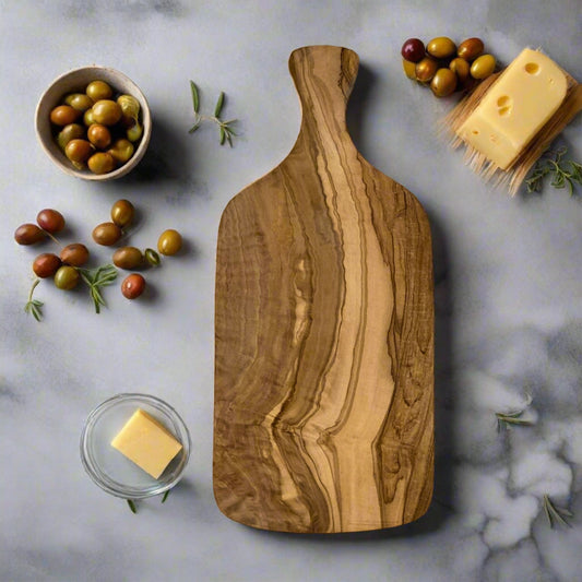 Olive wood paddle shaped chopping board with cheese and olives. 