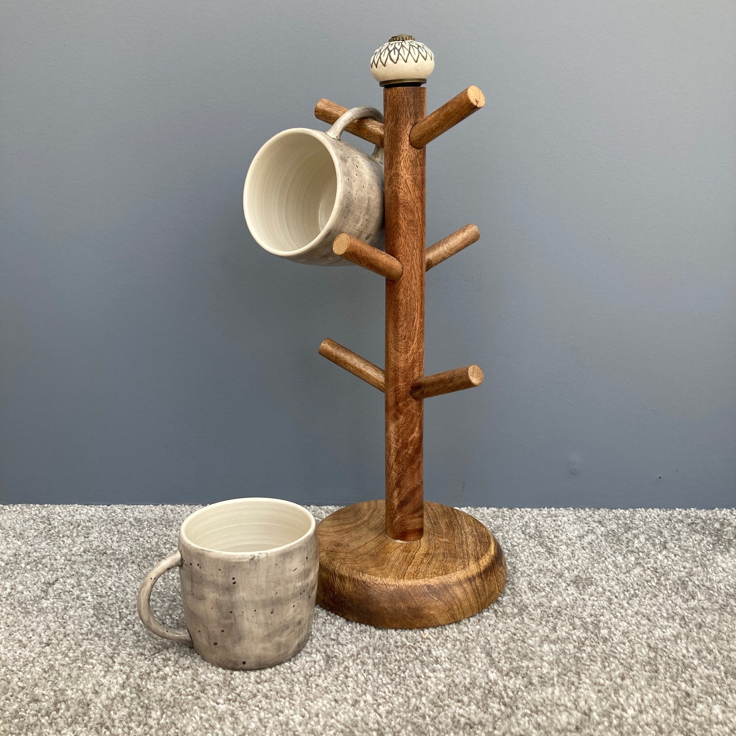 Dark Mango wood mug tree to hold up to 6 cups. 2 designs. One mug on tree, one mug off.