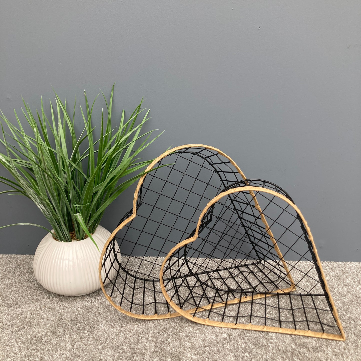 Heart shaped woven metal fruit baskets with raffia edging on their sides.