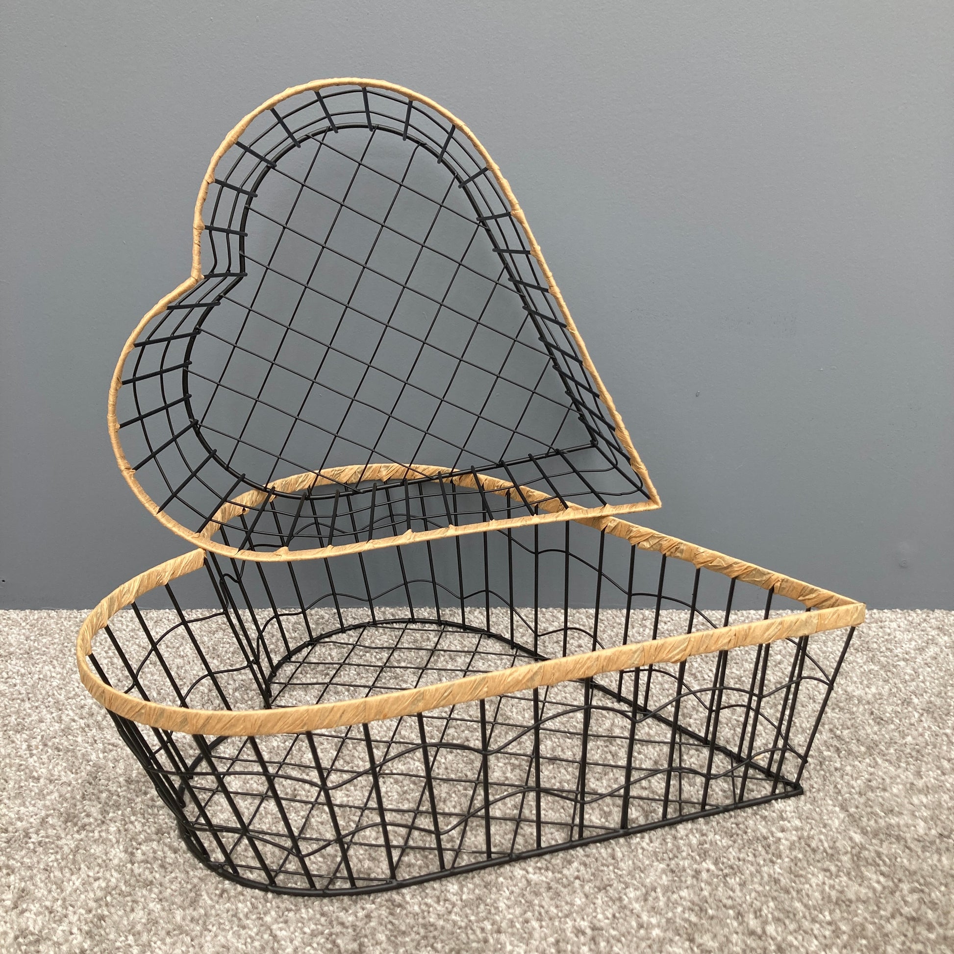 Heart shaped woven metal fruit baskets with raffia edging stacked on top of each other.