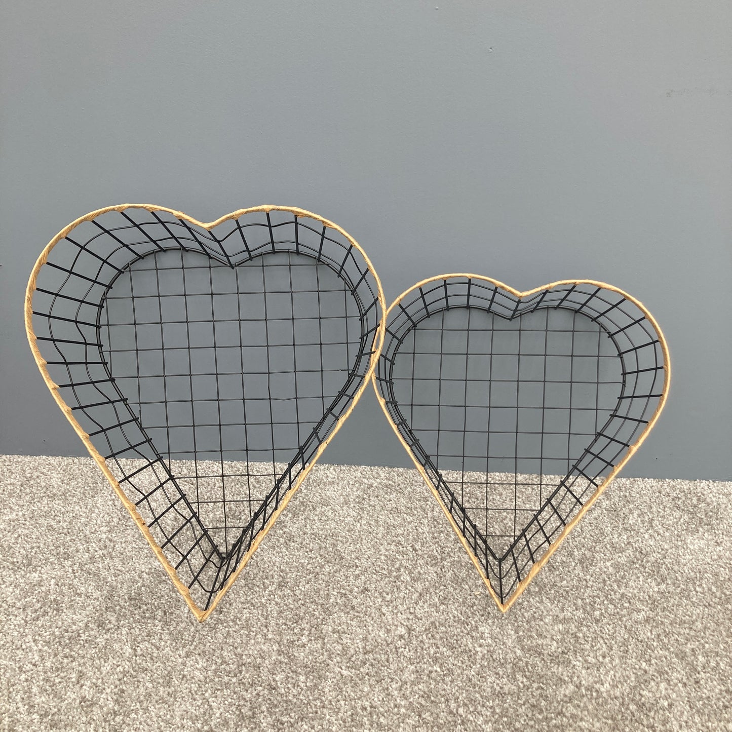 Heart shaped woven metal fruit baskets with raffia edging stood up.