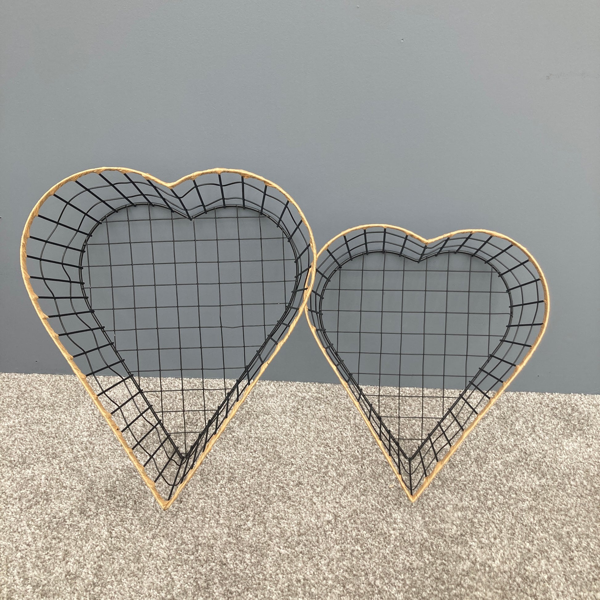 Heart shaped woven metal fruit baskets with raffia edging stood up.