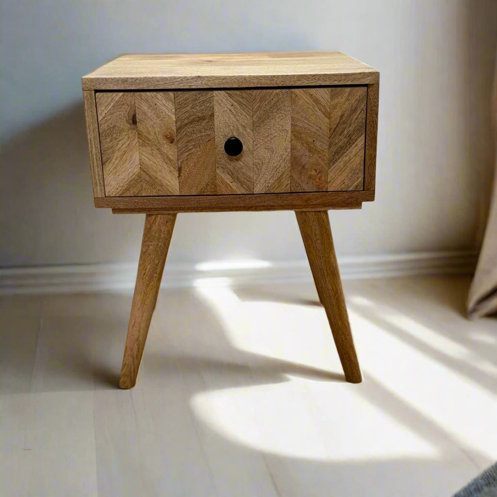 Wooden nightstand with a chevron patterned drawer on a wooden floor.