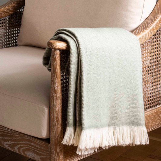Herringbone wool throw 170x130cm- Sage. Hanging over a chair. 