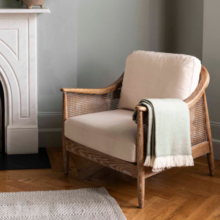 Herringbone wool throw 170x130cm- Sage. Hanging over a chair in the corner of a room. 
