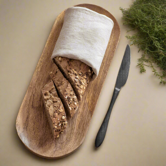Wooden bread board with sliced bread and a knife on a neutral background