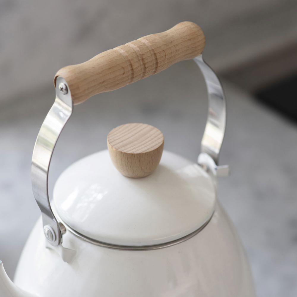 White kettle with wooden handle and lid knob on a neutral background