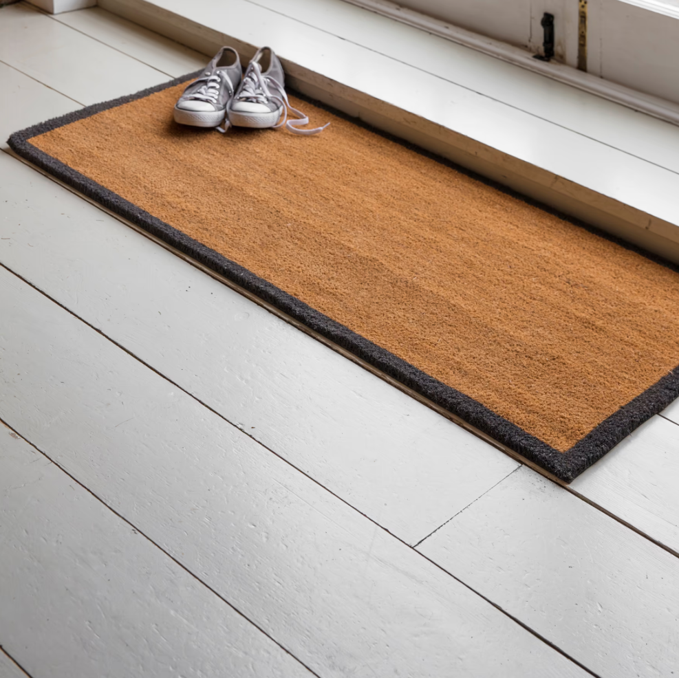 Doormat with shoes on a white wooden floor