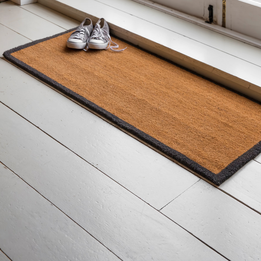 Doormat with shoes on a white wooden floor