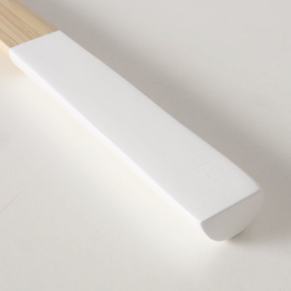 White rectangular object with wooden handle on a light gray background