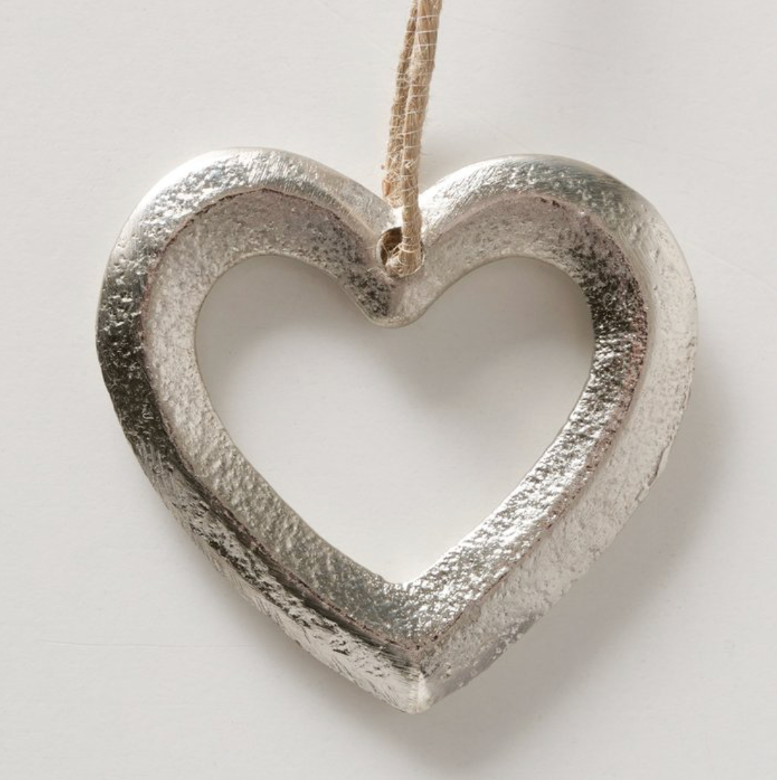 Silver heart-shaped ornament hanging against a light background