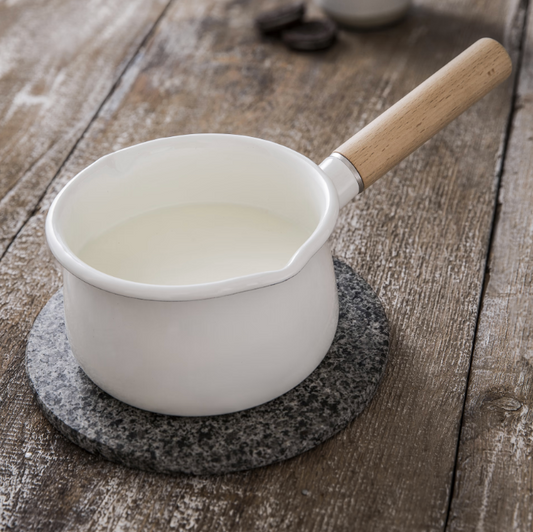 White saucepan with wooden handle on a wooden surface