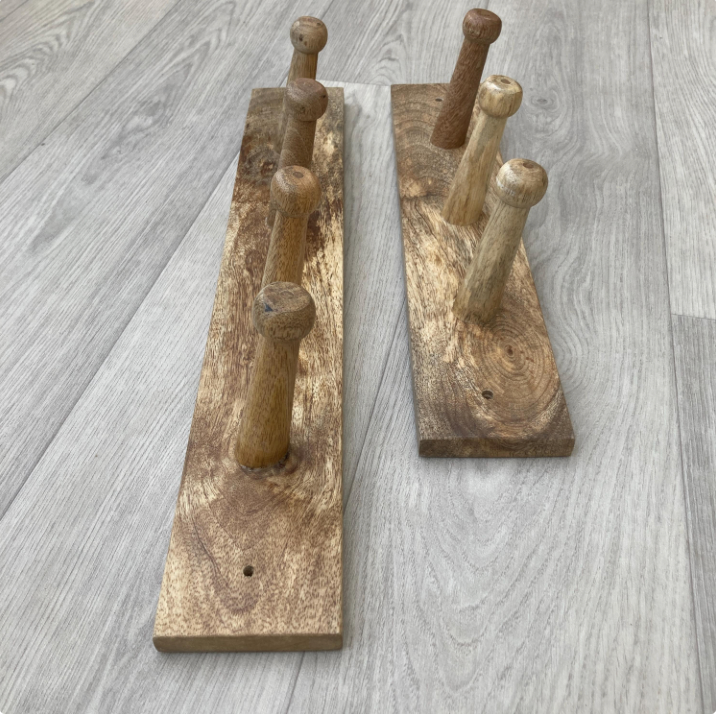 Two wooden coat racks with multiple hooks on a gray wooden floor.