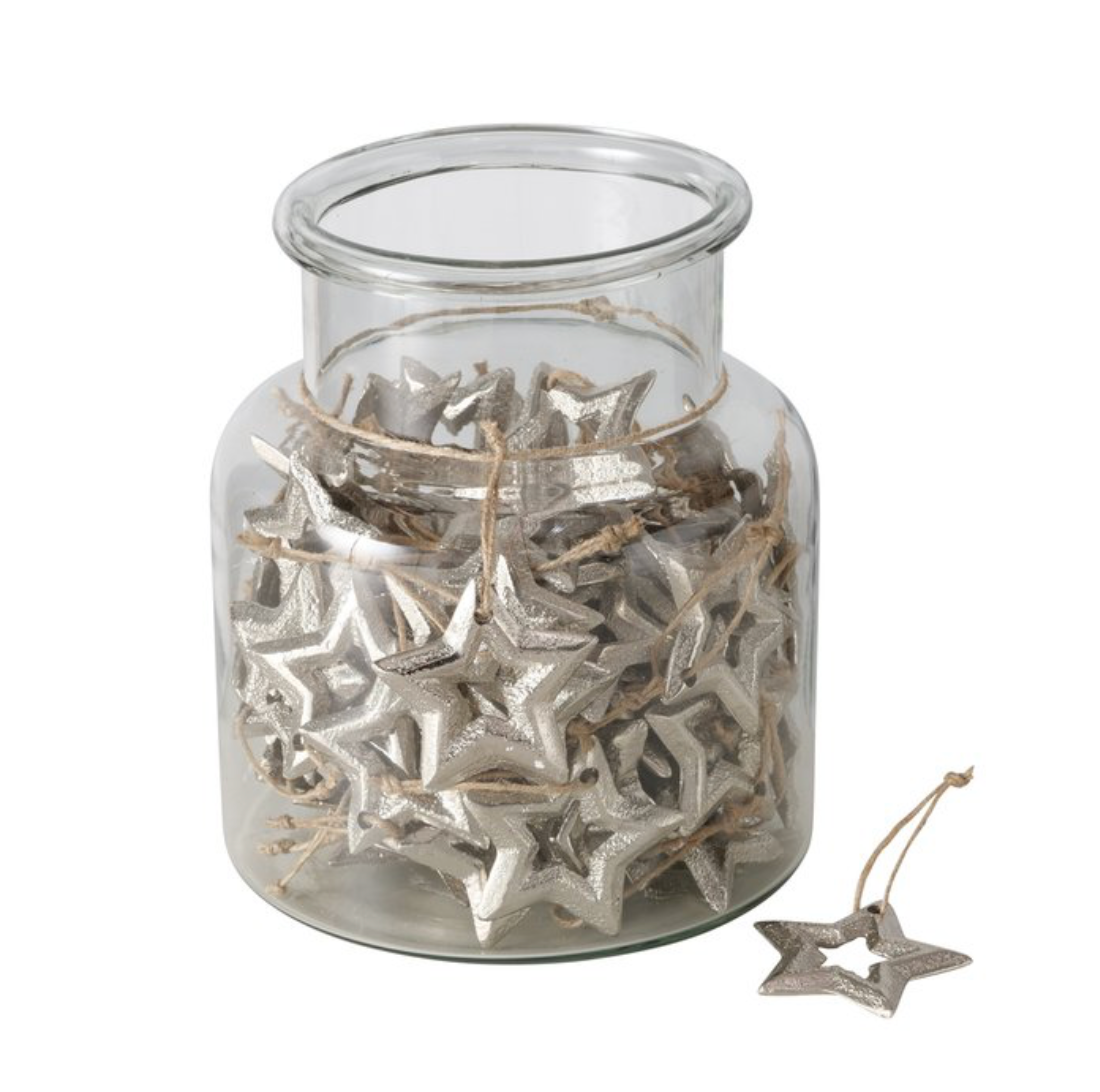 Clear glass jar filled with silver star-shaped decorations on a white background
