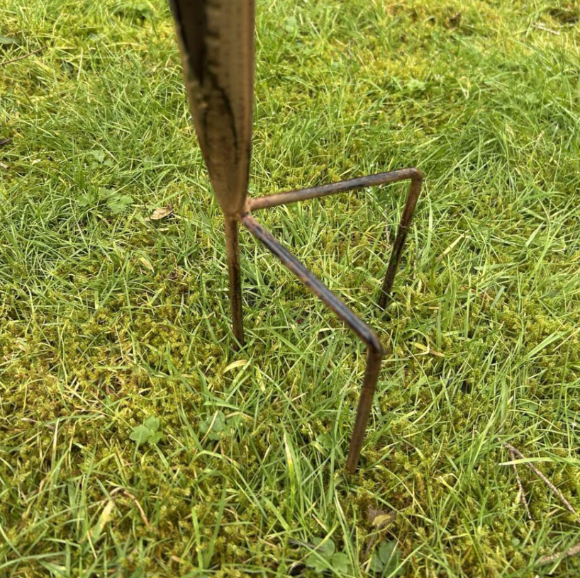 Metal garden tool with a curved blade on grass
