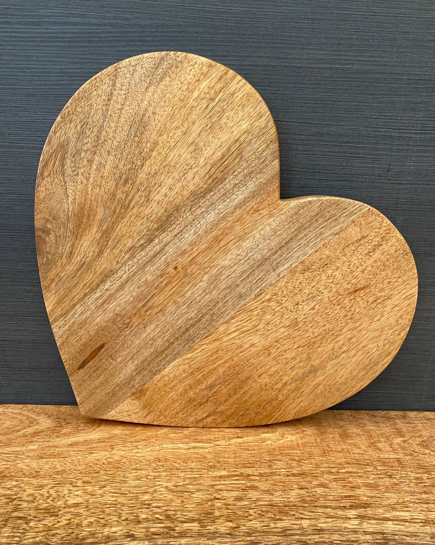 Large heart shaped Mango wood chopping board. No handle, board stood up. 