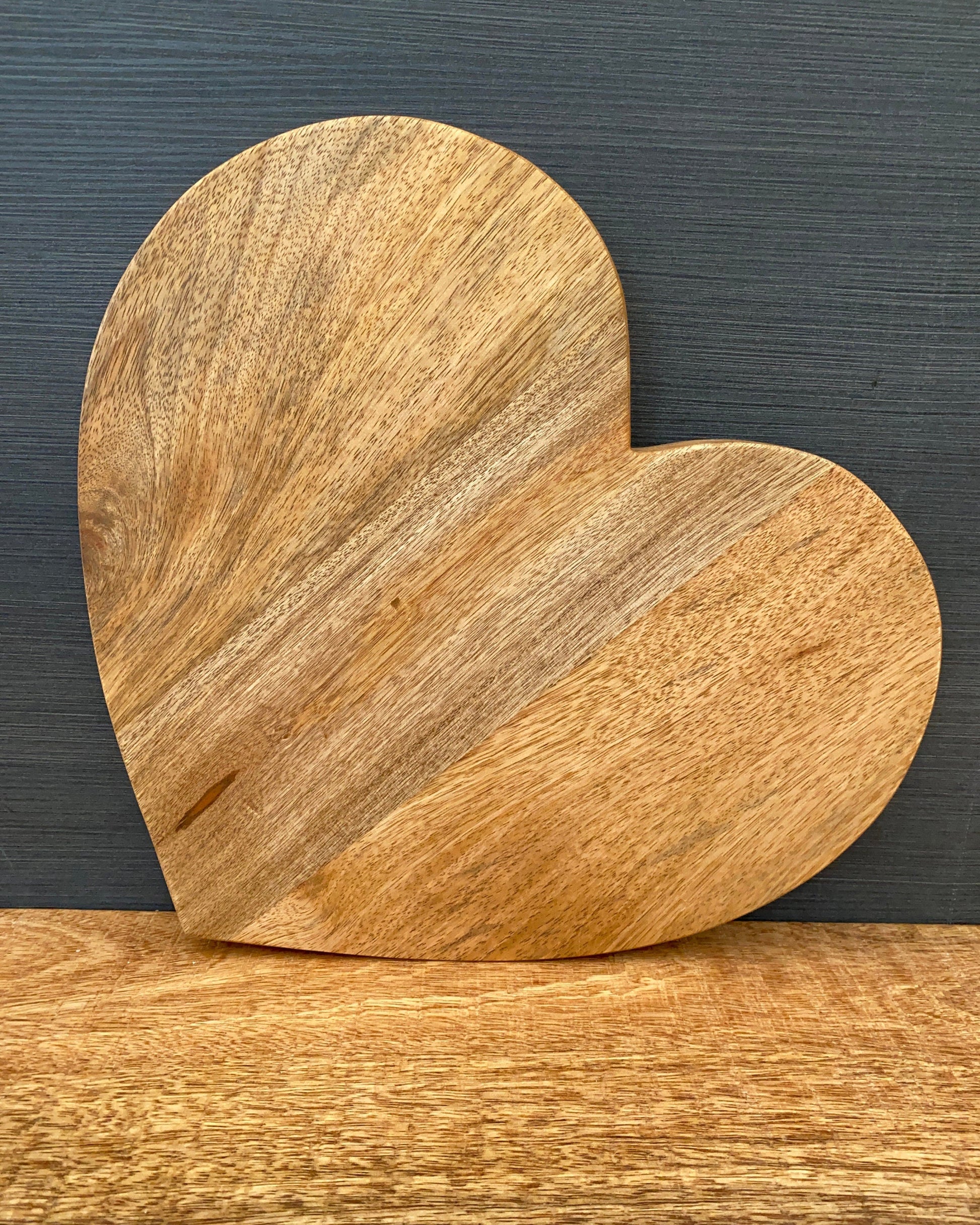 Large heart shaped Mango wood chopping board. No handle, board stood up. 