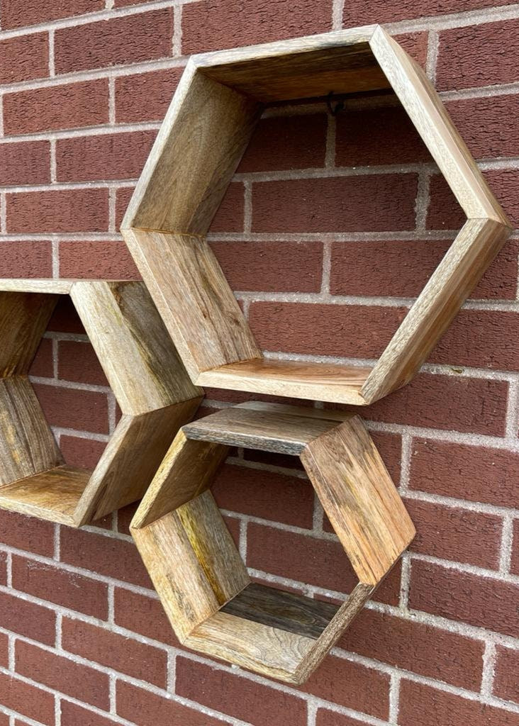 Hexagonal Mango wood floating wall shelves mounted on brick wall. 
