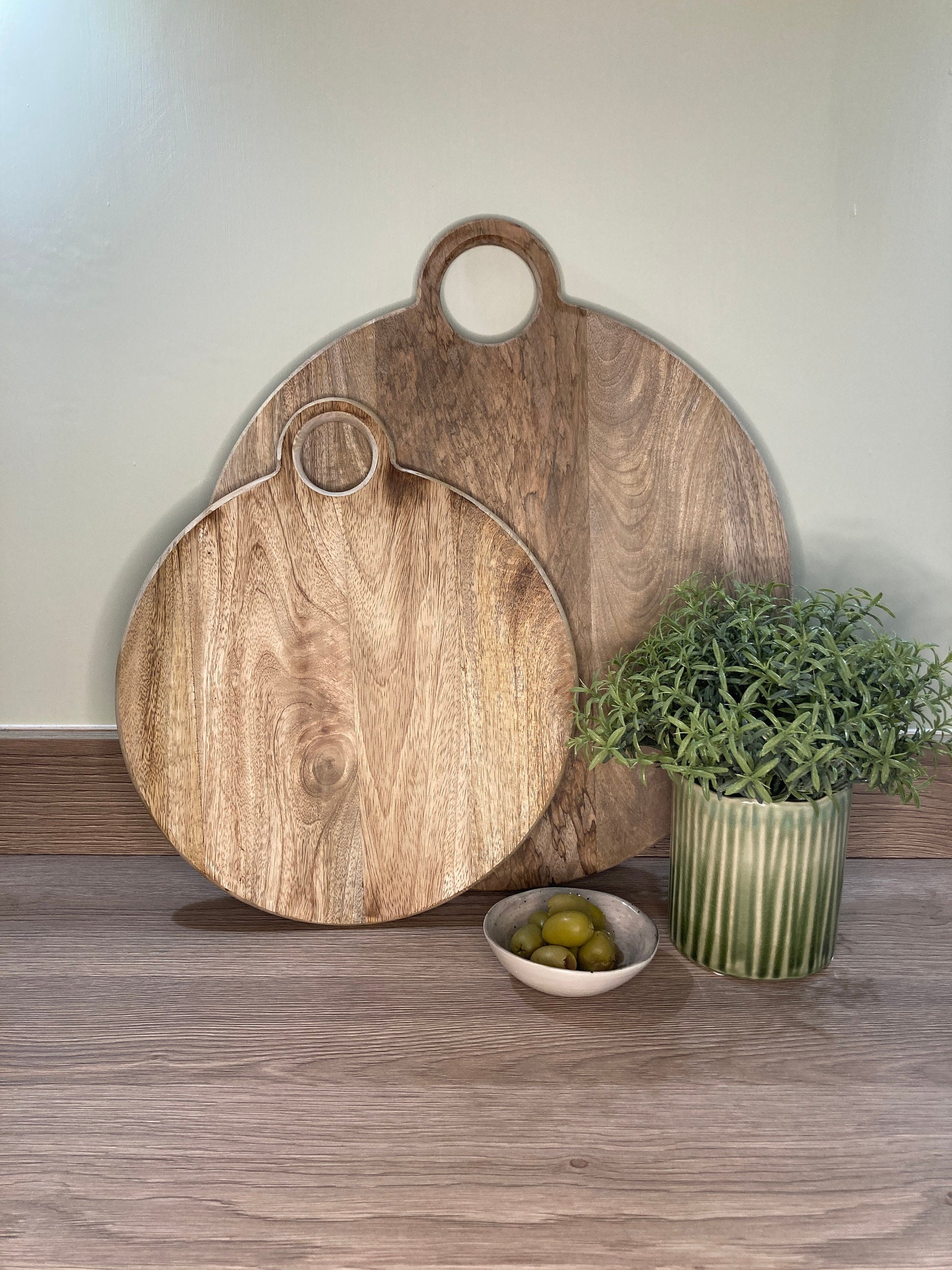 Round loop handled food boards made from solid Mango wood. on a counter top