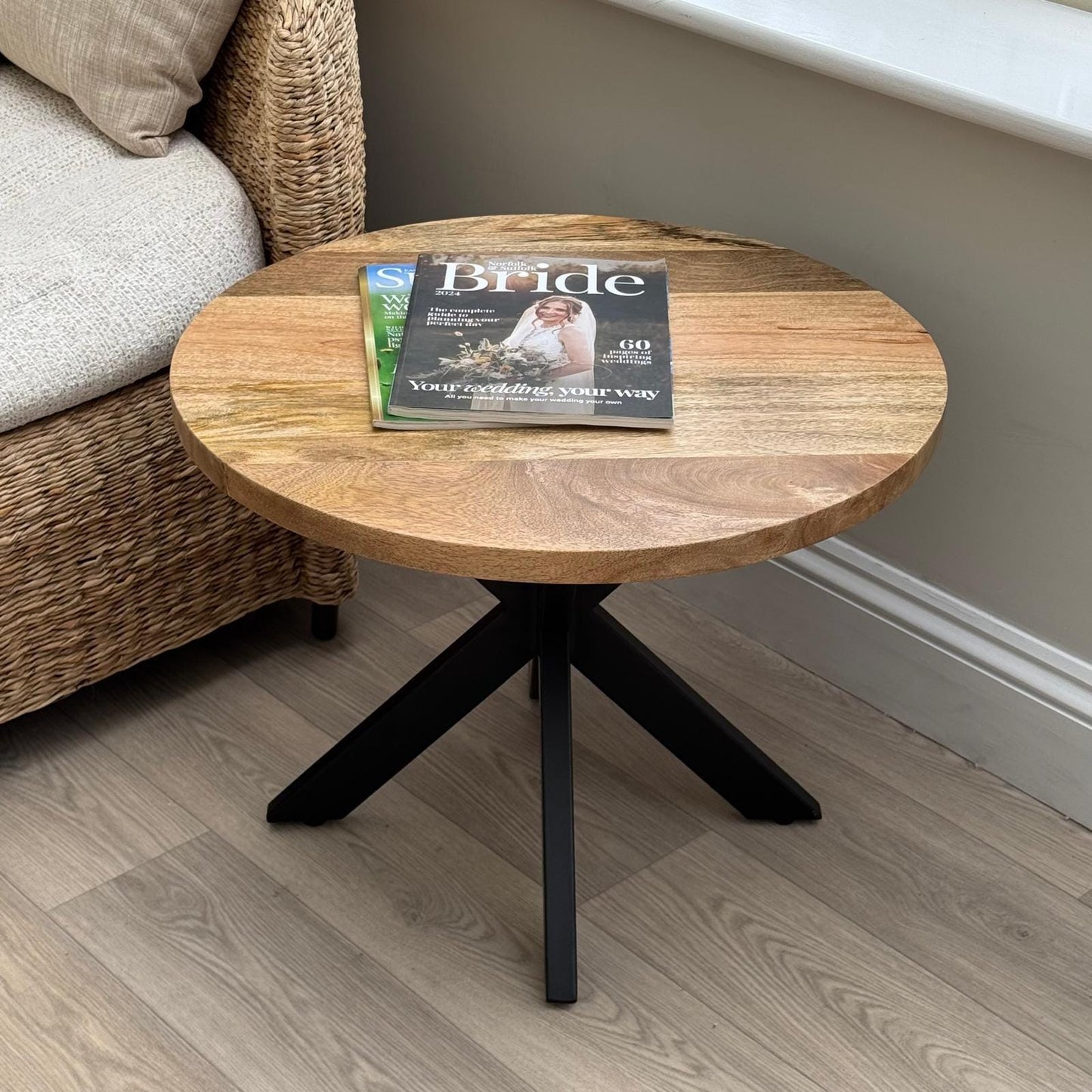60cm round Mango wood top coffee table with black metal legs. Shown with magazines. 