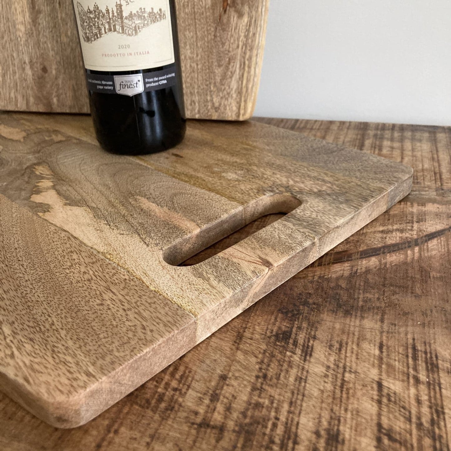 Wooden cutting board with a bottle of wine on a wooden surface